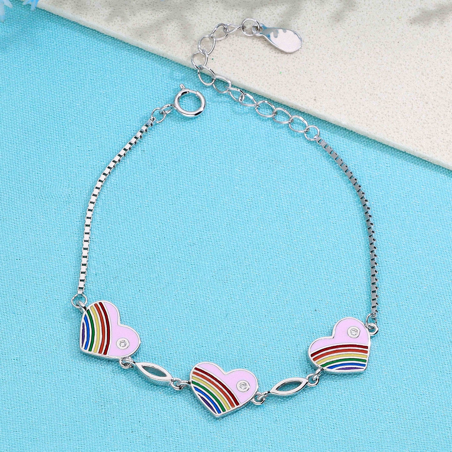 Sterling silver bracelet with three pink heart charms featuring rainbow